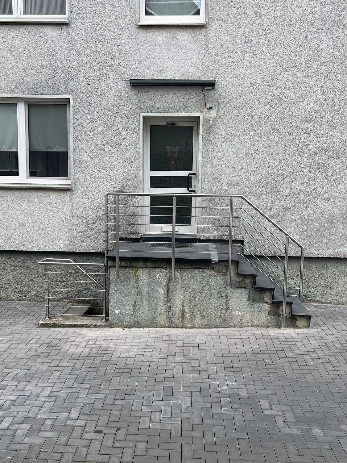 Edelstahlgeländer mit Querstäben an einem Eingangspodest und am Kellerabgang