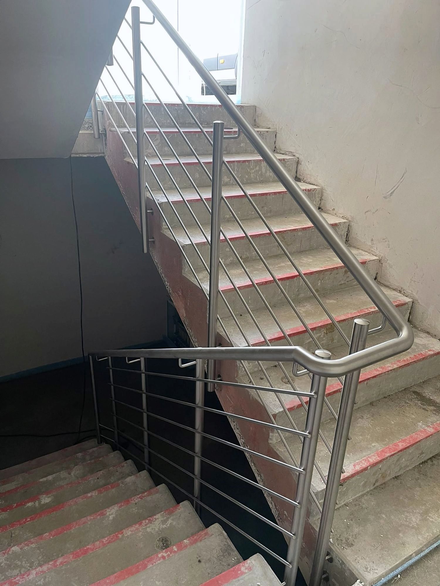 Treppengeländer aus Edelstahl mit waagerechten Stäben und rundem Handlauf in einem Treppenhaus